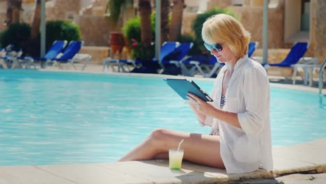 Woman-Relaxing-By-The-Pool-Enjoying-The-Tablet