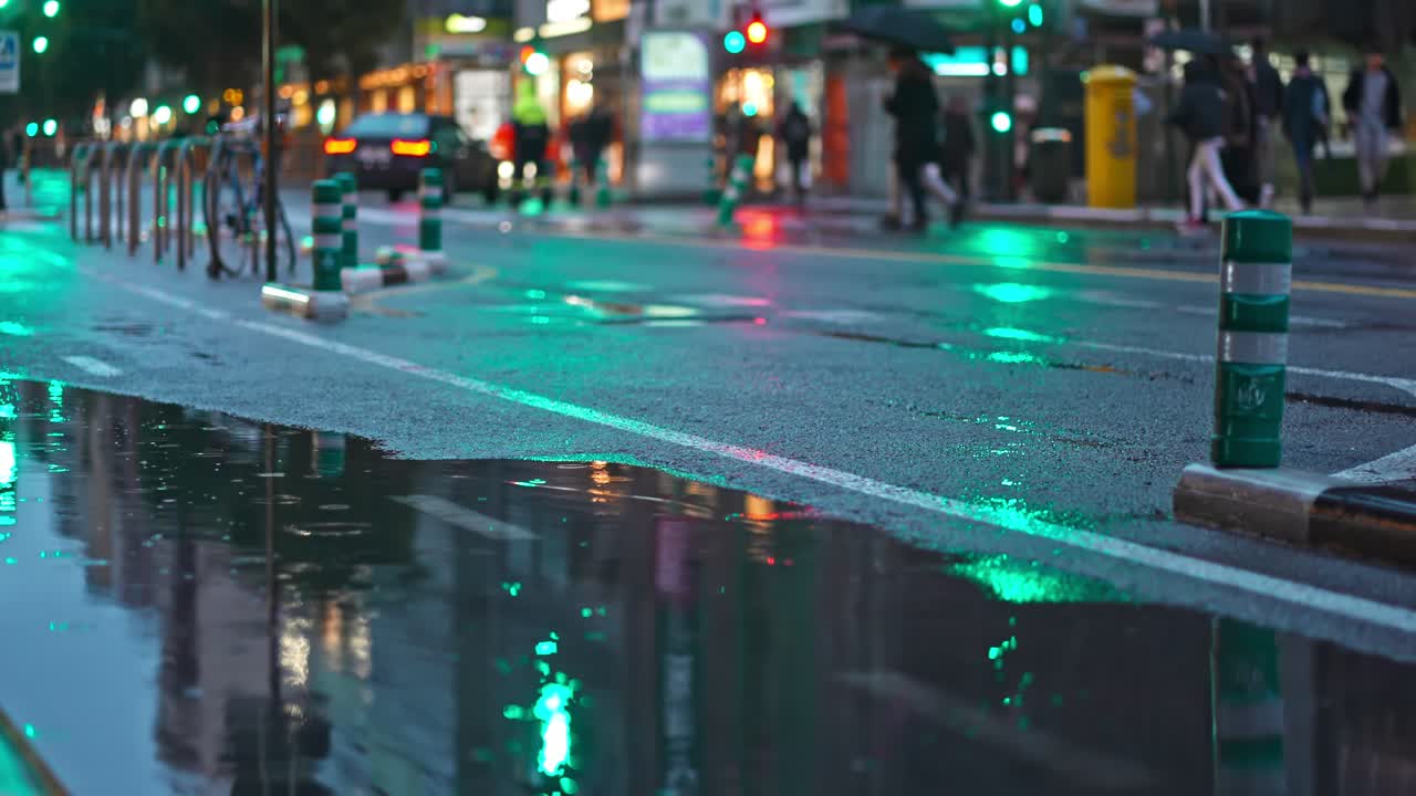 Bike lane with puddle on the street, bike and electric scooter passing by the water in a rainy night. Light reflecting on the asphalt.