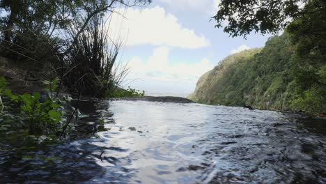 Unique-perspective-of-a-tranquil-creek-flowing-over-the-edge-of-a-natural-infinity-rock-pool