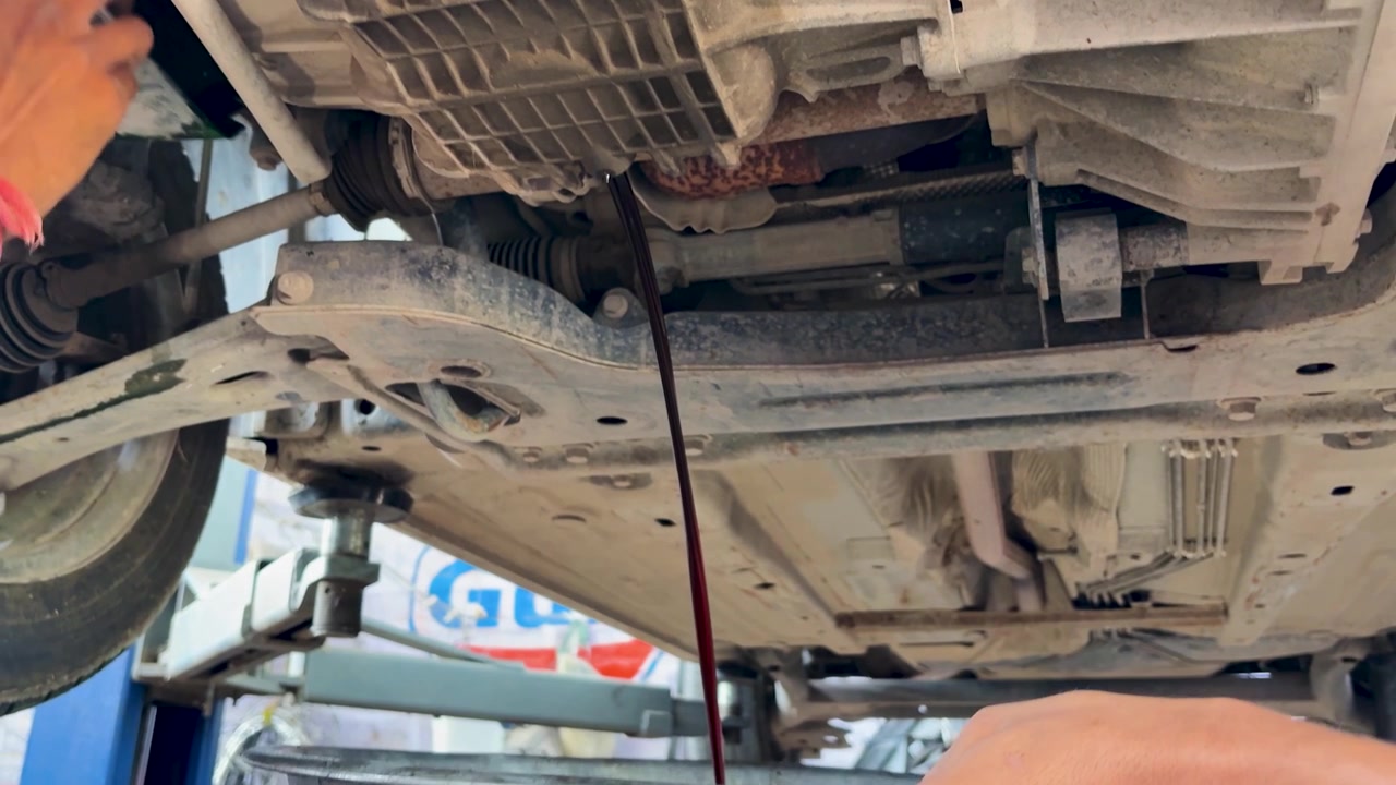 Vehicle Engine Oil Drain Process At Auto Repair Workshop During Maintenance