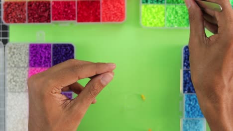 close-up of hands crafting a rainbow necklace with colorful beads, vibrant creative hobby