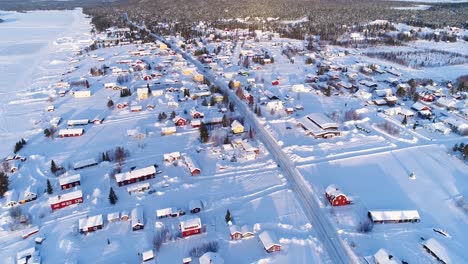 an aerial view shows the colorful homes near a forest in the wintry town of kiruna sweden