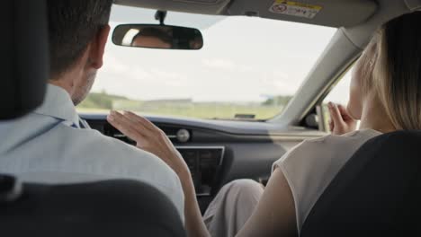 vista posterior de una alegre pareja caucásica de mediana edad cantando durante un viaje en coche.