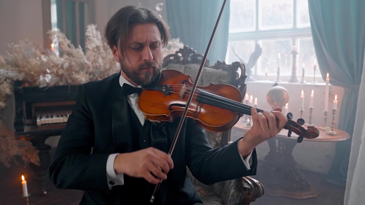 Uomo elegante in abito formale che suona il violino in una stanza a lume di candela