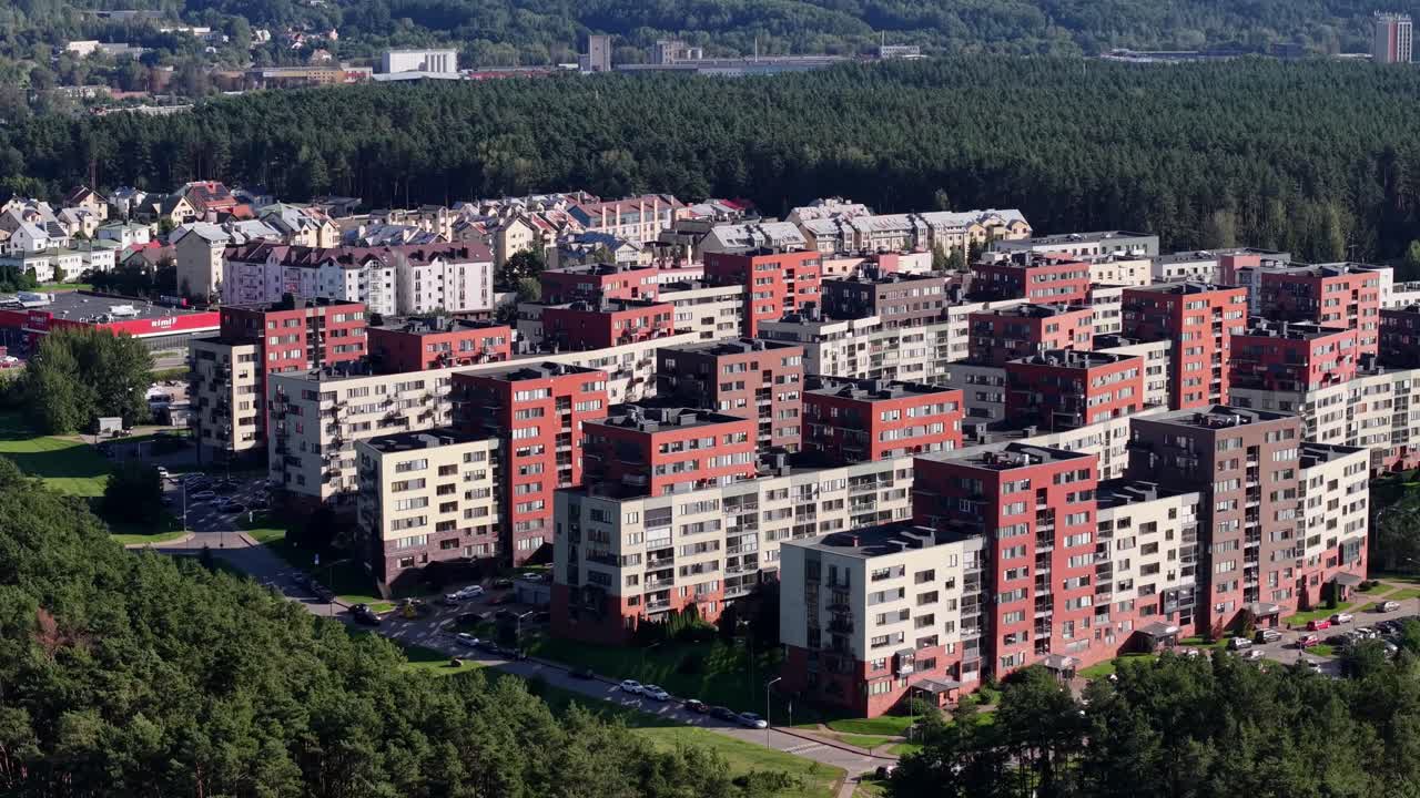 Drooni etenee Vilnan Lazdynain alueen yläpuolella paljastaen yhtenäisiä kerrostaloja, joita reunustavat tiheä metsä ja vehreä asuinympäristö