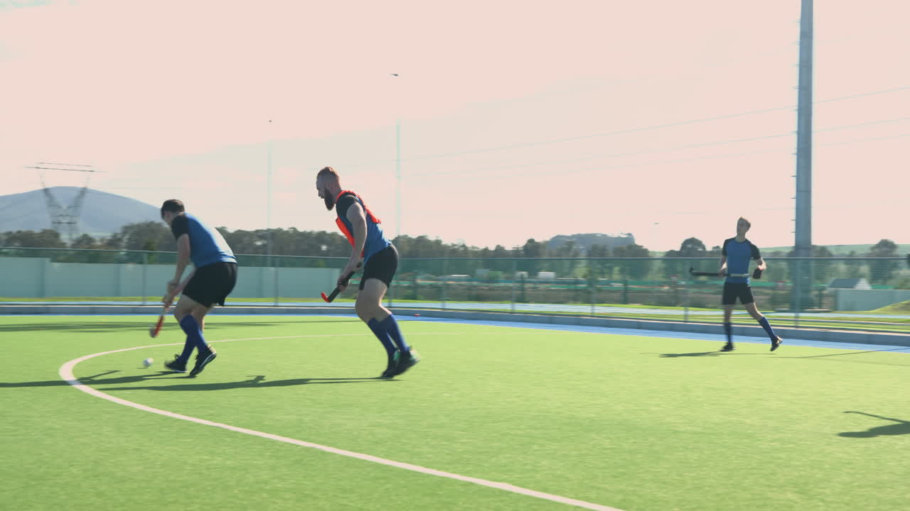Playing field hockey, men competing intensely on outdoor sports field