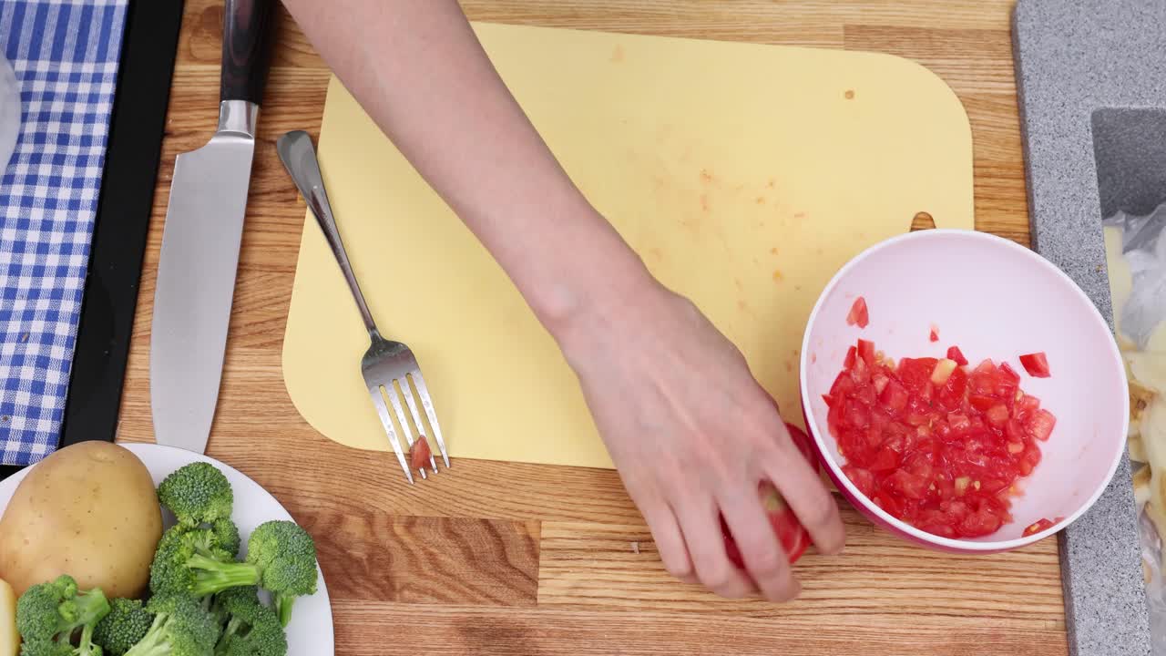 Una donna sminuzza e grattugia pomodoro crudo cucinando in cucina.