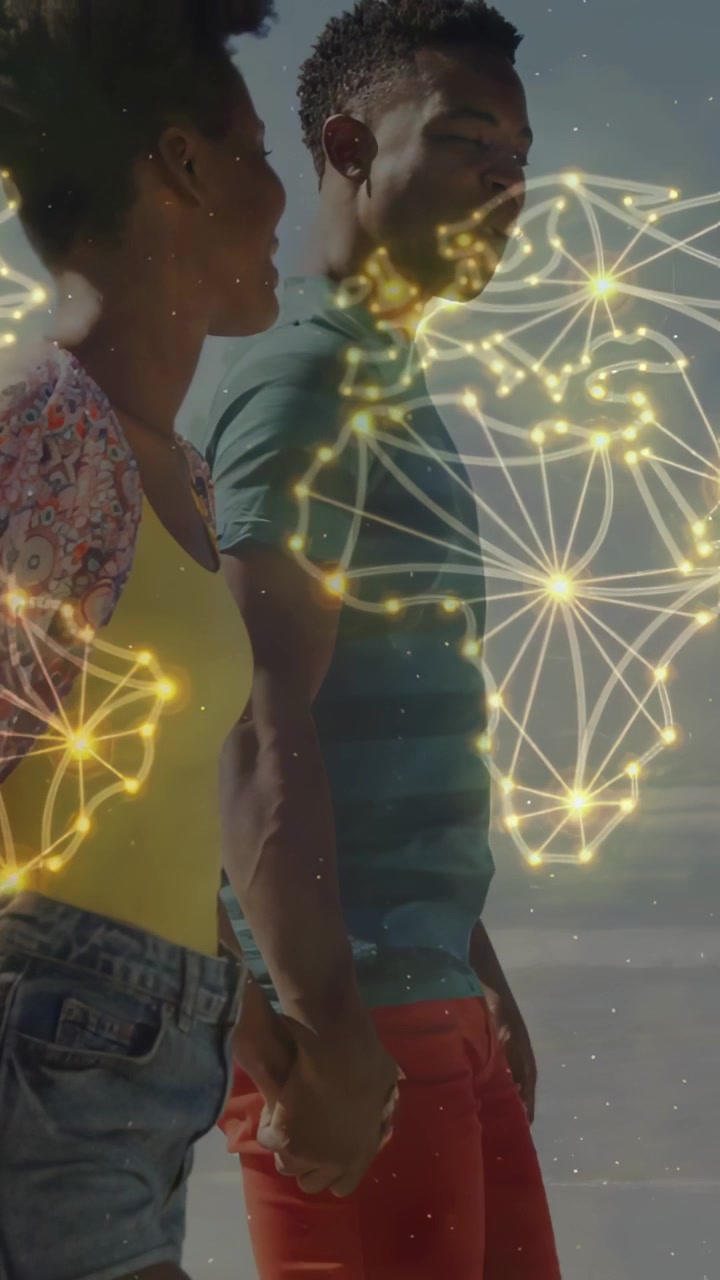 Walking couple in yellow top smiling for leisure holding hands on beach camera closing gold overlay