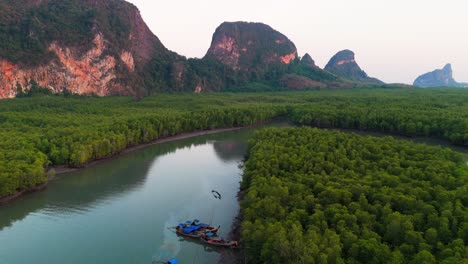 River boats anchored in estuary of mangrove forest in Phang Nga Bay, Thailand, limestone cliffs, lush islands, and winding waterways, aerial dolly