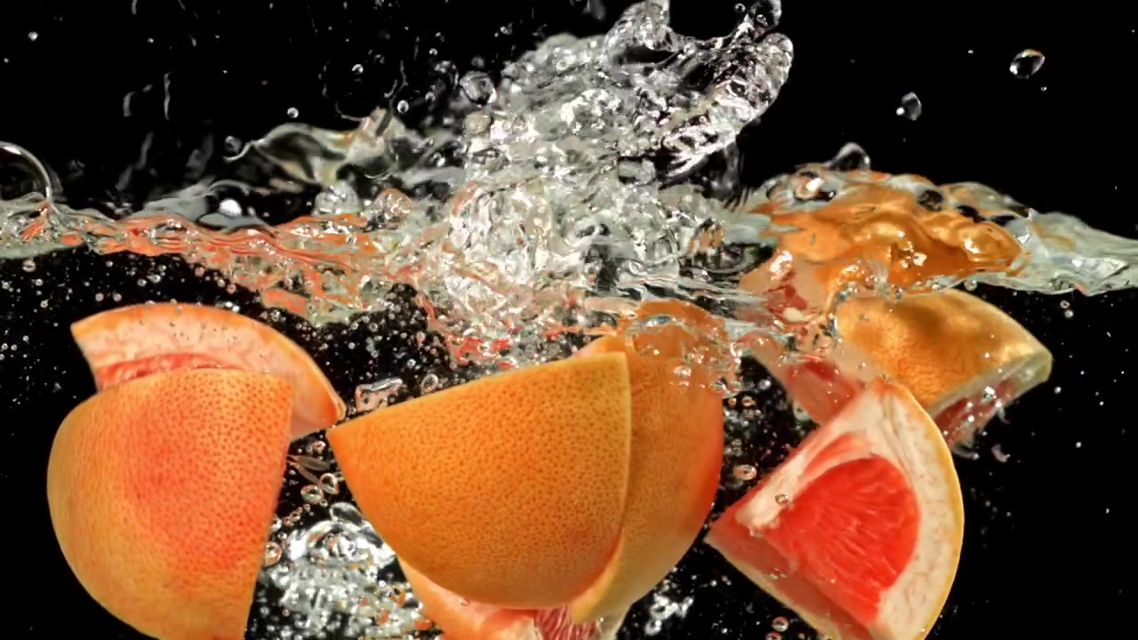 Frische Grapefruitscheiben spritzen mit Blasen ins Wasser