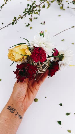 hand holding a flower arrangement with a "still i rise" tattoo