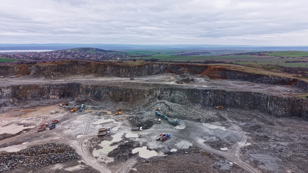 Granite quarry with heavy machinery and rocky landscape in a rural area during cloudy weather