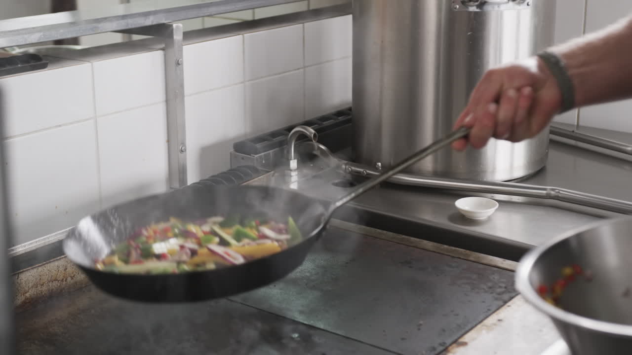chef caucásico fritando verduras en una sartén en la cocina, en cámara lenta