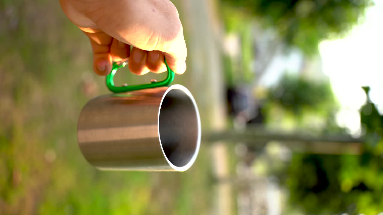 taza de camping vertical con café caliente que muestra un paisaje de paraíso natural rodeado