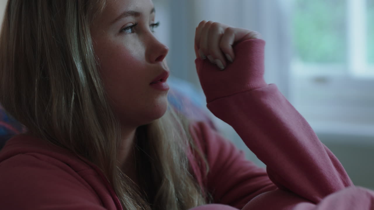 집에서 혼자 있는 슬픈 십대 소녀 우울한 기분의 십대 소녀는 침실에 앉아 감정적으로 헤어지는 것을 생각하고 있습니다.