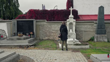 girl standing in front of a tombstone while visiting a graveyard