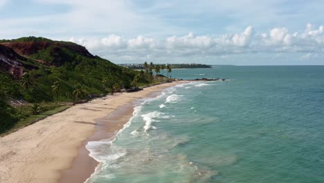 Hermosa-Muñeca-Aérea-Con-Drones-En-Una-Toma-De-La-Costa-Tropical-De-Paraiba,-Brasil,-Cerca-Del-Famoso-Destino-Playa-De-Coqueirinhos-Con-Palmeras,-Altos-Acantilados,-Arena-Dorada-Y-Aguas-Cristalinas-Del-Océano