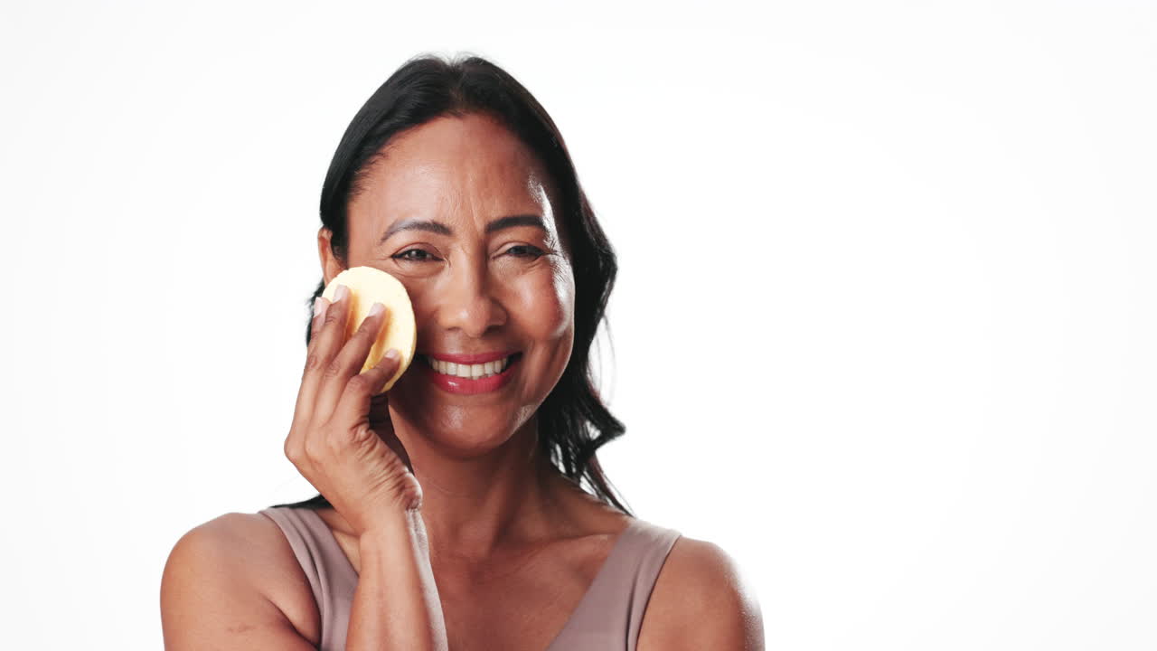 Happy Mature Woman Applying Makeup with Sponges in Studio