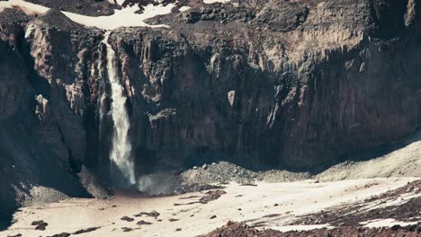 Static-shot-of-an-otherworldly-single-waterfall-falling-amidst-alien-looking-terrain