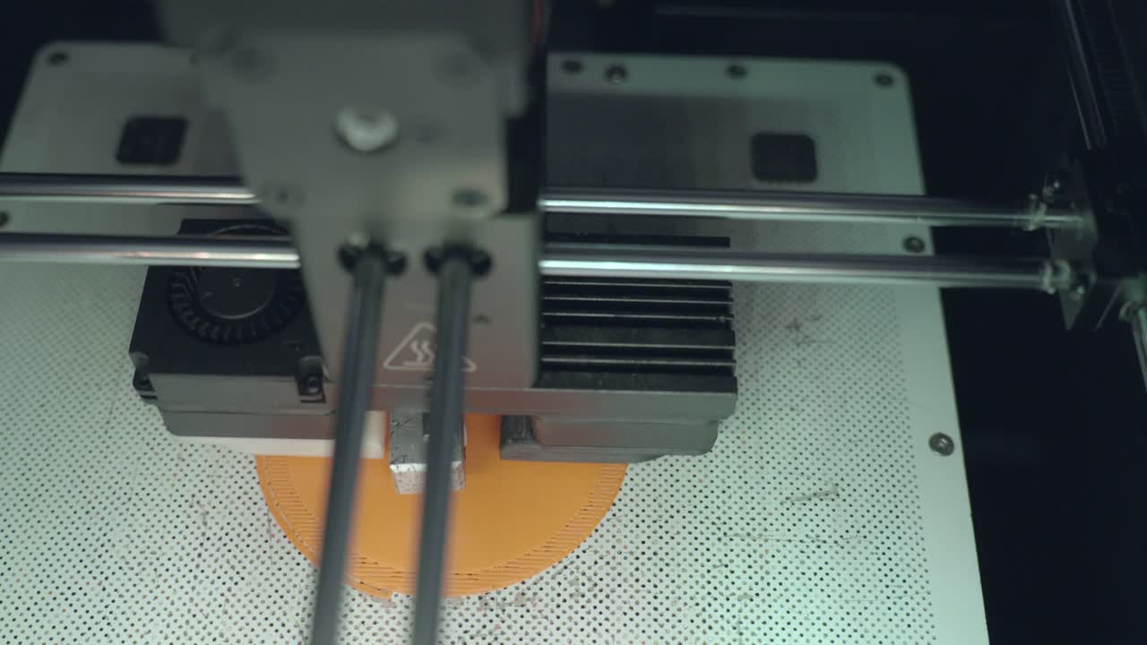 impresora 3d de arriba hacia abajo creando una base de círculo naranja, primer plano