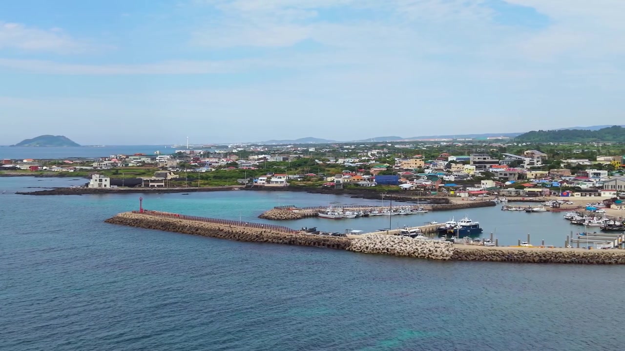 Toàn cảnh từ trên cao cảng Sinchang ở Hangyeong, đảo Jeju với làn nước màu ngọc lam, tua-bin gió, đê chắn sóng và làng chài ven biển.