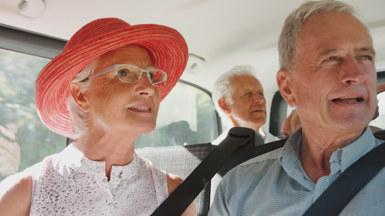 grupo de amigos mayores sentados en la parte trasera de un transportista de personas que está siendo llevado de vacaciones