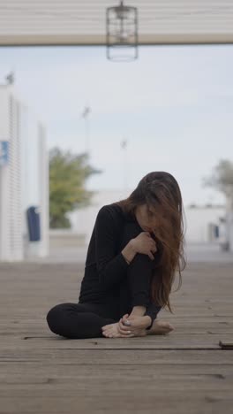 woman sitting alone on wooden floor, expressing contemplation or sadness