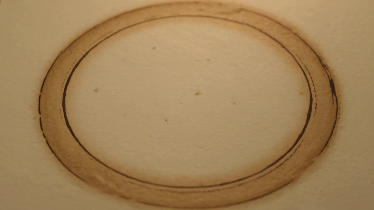 La fotocamera che mette a fuoco rivelando una macchia ad anello marrone su un foglio granuloso beige chiaro, con contrasto crescente