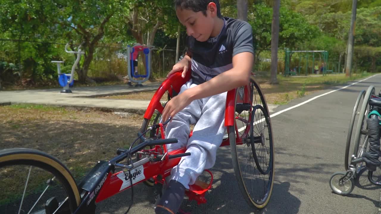 패러사이클 경주에서 핸드바이크를 타기 위해 준비하는 장애 아동