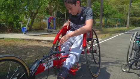 un niño con discapacidad preparándose para andar en handbike en una carrera de paraciclismo
