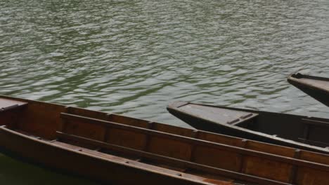 Calming-view-of-wooden-long-boats-sitting-quietly-on-riverside-dock-in-Tubingen,-Germany,-Europe,-panning-shot