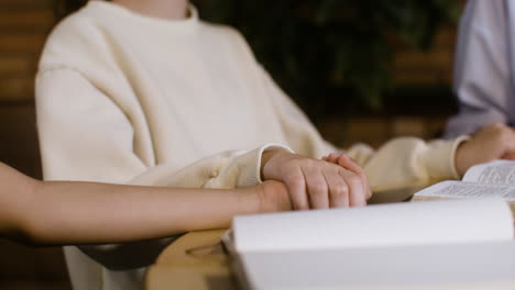 Closeup-of-books-on-table-and-kids-holding-hands