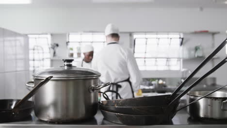 dos cocineros varones enfocados preparando comidas en la cocina, en cámara lenta