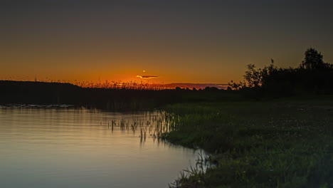 amanecer dorado sobre un lago con el sol brillante reflejándose en el agua - lapso de tiempo de ángulo bajo