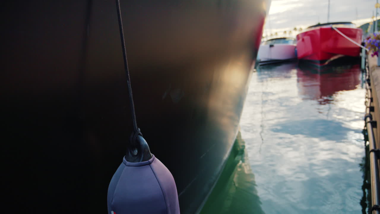 Modern red and white yacht docked in calm marina waters with clear reflections
