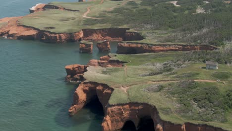 Pilas-De-Mar-Y-Acantilados-Rojos-De-Las-Islas-Magdalen-Con-Campos-Verdes-Y-árboles-Junto-Al-Río-San-Lorenzo-En-Quebec,-Canadá