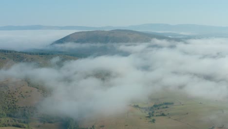 aerial flyover shot high above the clouds looking out on a pastoral landscape