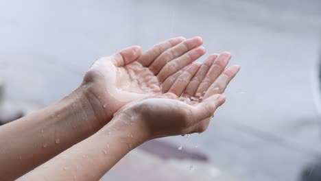 two hands holding falling rain, rainy day, stormy season, catches rains on palm, rainy season slow motion, on the street side, air moist condensation, acid rain measurement, isolated close up