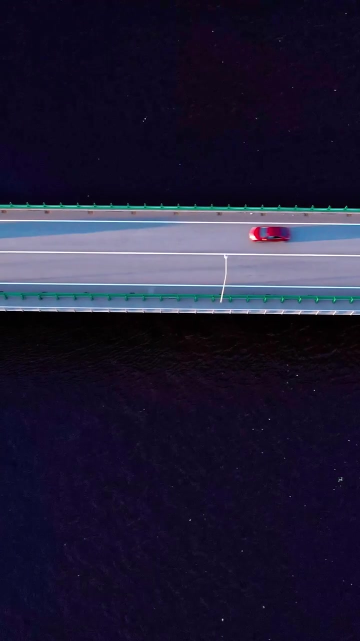 Auto che percorrono un ponte sull'acqua in Lettonia al tramonto
