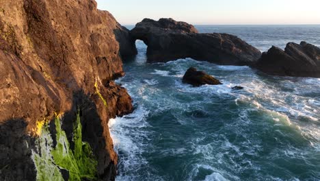 Costa-De-Oregon-Costa-Irregular-Mientras-Algunas-Olas-Poderosas-Chocan-Contra-Las-Paredes-De-Roca-Con-Un-Paso-Elevado-De-Un-Arco-En-El-Océano