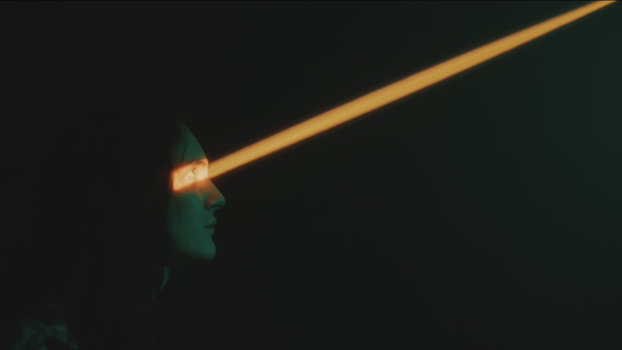 Young Man Looking Up on Light Beam in Dark Studio
