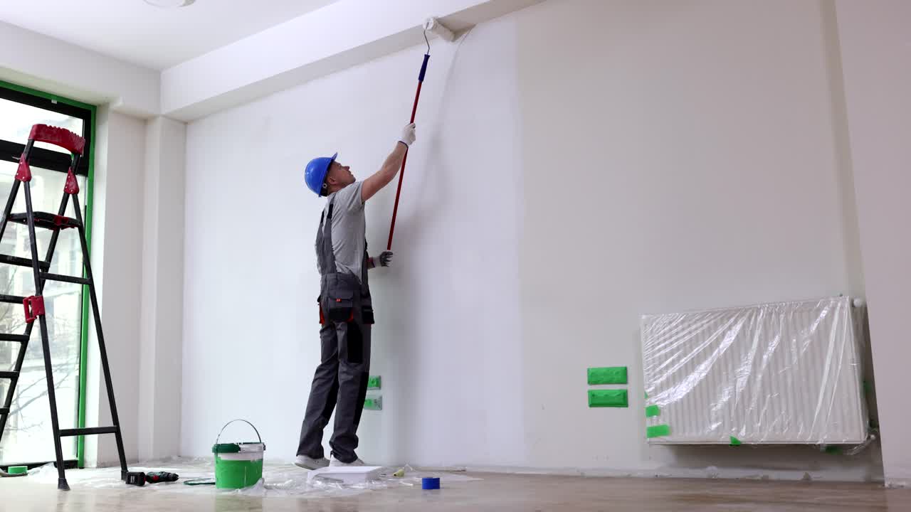 Painter paints the wall with roller