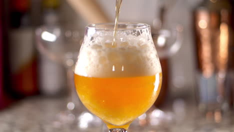 Slow-Motion-of-craft-Beer-being-poured-in-to-a-tulip-glass,-bar-background