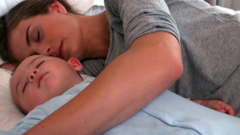 un bebé durmiendo en la cama con su madre