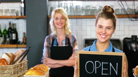 portrait of waitress standing with open sign board