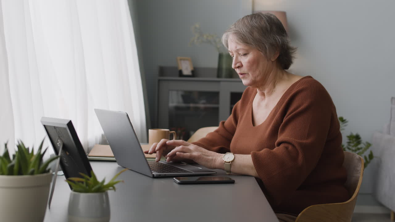 Focused Woman Typewritting At Laptop Sitting At Desk At Home 1