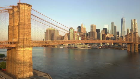 AERIAL:-Flight-towards-Brooklyn-Bridge-with-Manhattan-and-East-River-view-at-Sunrise,-Sunset