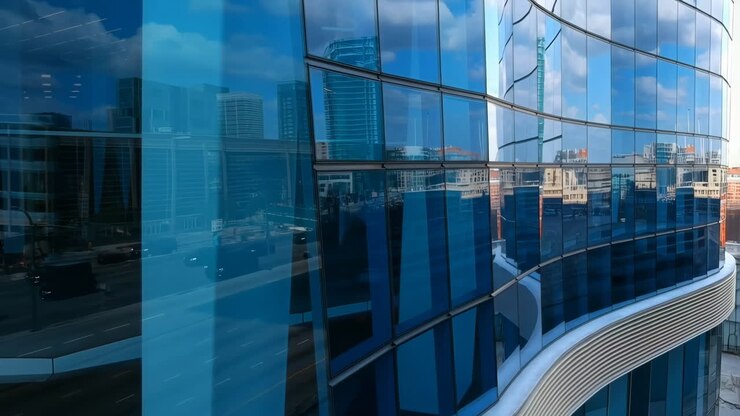 Moderno grattacielo di vetro blu con riflessi della città e del cielo