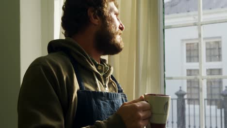 Craftsman-having-coffee-while-looking-through-window-4k