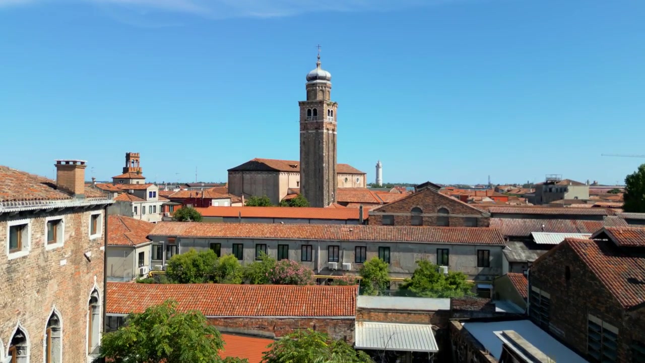 Vista dal tetto che rivela la torre della Chiesa di San Pietro Martire sopra gli edifici di Murano, in una giornata di sole.
